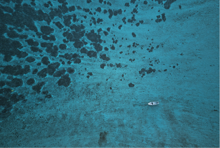 A boat floats peacefully in a coral reef in Mauritius.